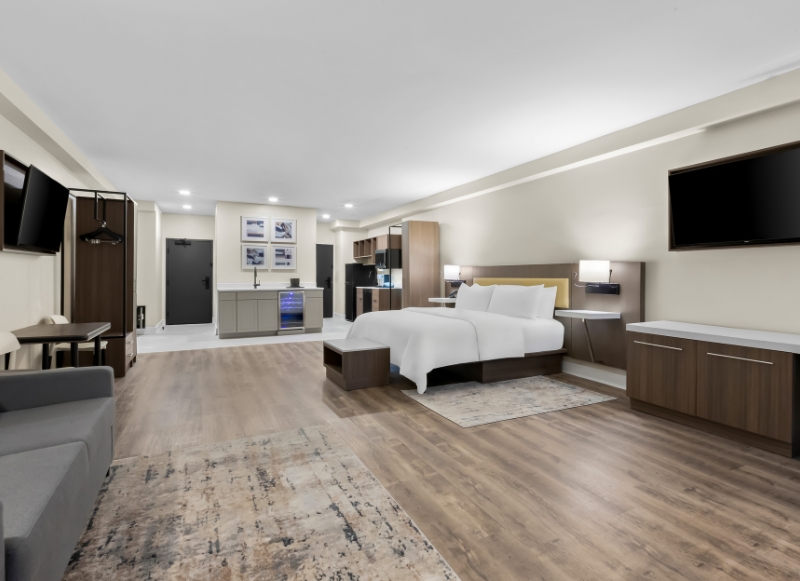 Comfortable hotel room with a couch, television, and bed, conveniently near Wall Stadium Speedway.