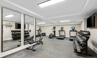 A fitness center at Hotel Tinton Falls NJ, featuring mirrors and various gym equipment for workouts.