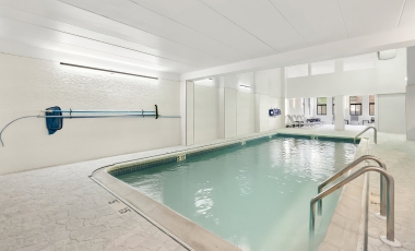 Indoor pool at Hotel Tinton Falls, NJ, featuring a bright white building and tranquil water.