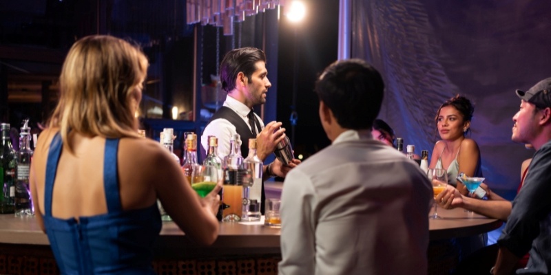 A group of people enjoying drinks and conversation around a bar during the New Jersey Shore itinerary evening.