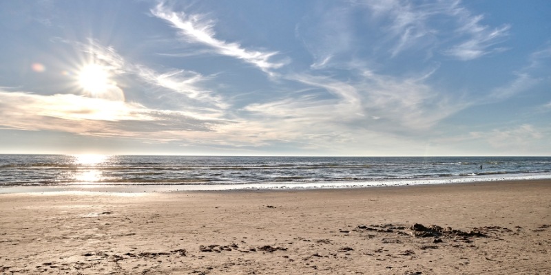 A sunny beach at the New Jersey Shore, with sunlight sparkling on the water, perfect for Day 3 in Long Branch.