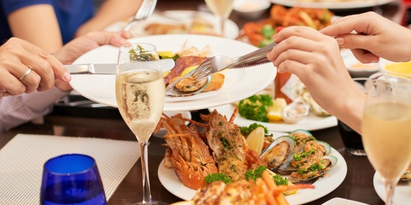 A group of people enjoying seafood and champagne at a restaurant, highlighting dining options on a New Jersey Shore itinerary.