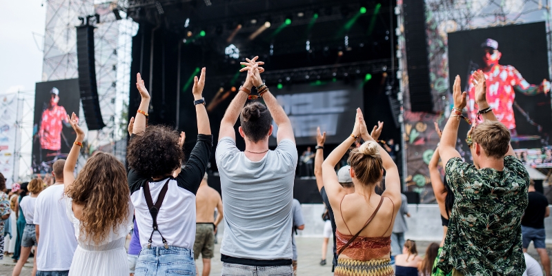 A crowd of people at a music festival on the New Jersey Shore, all raising their hands in excitement and unity.