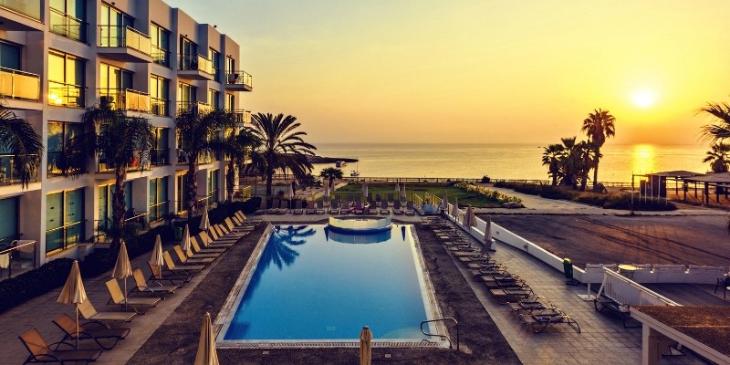 A hotel with a pool at sunset, overlooking the ocean, highlighting the beauty of the Jersey Shore.