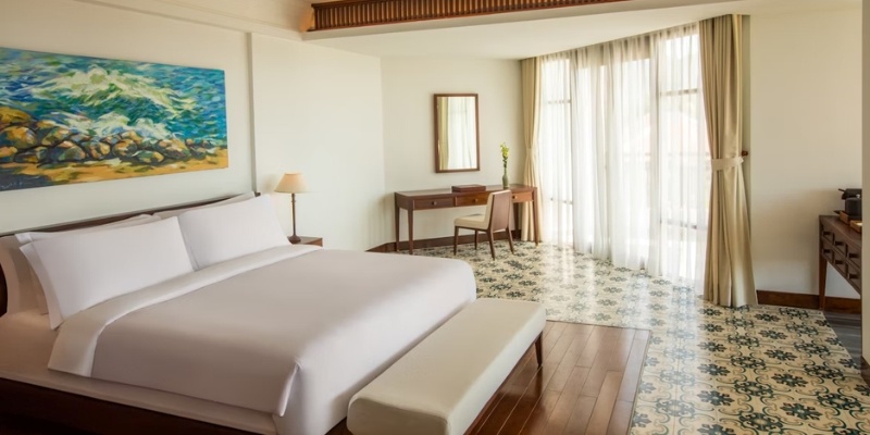 A hotel room featuring a large bed and a decorative painting on the wall, showcasing the Grand Hotel Cape May.