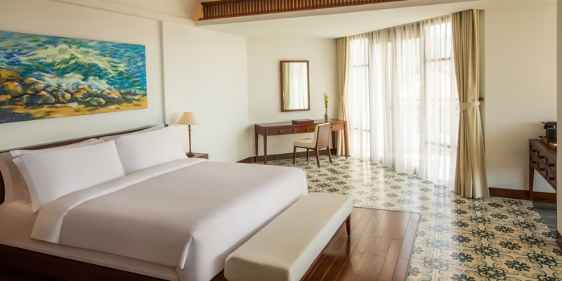 A hotel room featuring a large bed and a decorative painting on the wall, showcasing the Grand Hotel Cape May.
