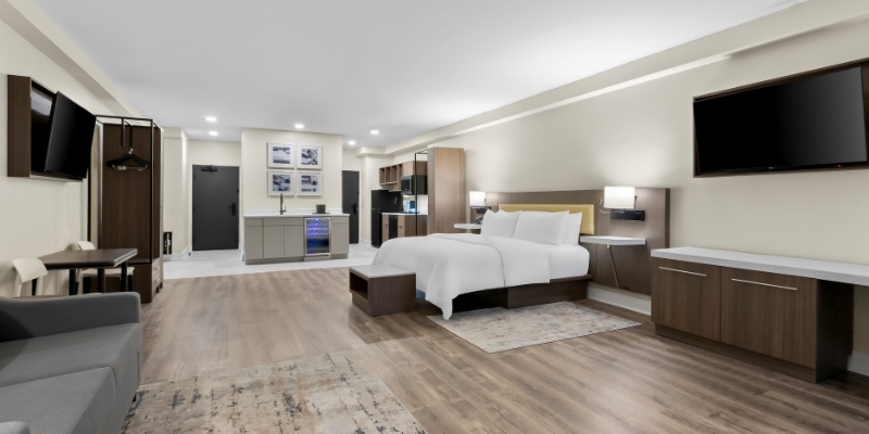 Modern hotel room featuring a bed, desk, and television at Latitude Suites, one of the Best Hotels in Jersey Shore.