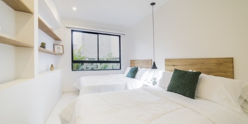 A small room featuring two beds against white walls, highlighting the inviting atmosphere of The StarLux Hotel & Suites.