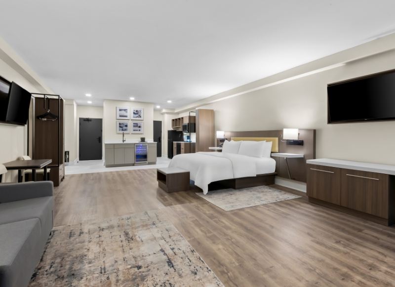 Modern hotel room featuring a bed, desk, and television, located Latitude Suites Hotel near Tinton Falls Shopping Center.