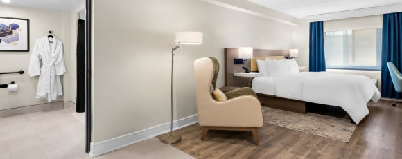 Cozy hotel room with a bed, chair, and desk, perfect for extended stays near Tinton Falls Shopping Center.