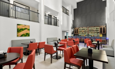 A modern restaurant featuring red chairs and tables, located at a hotel near Tinton Falls Shopping Center.