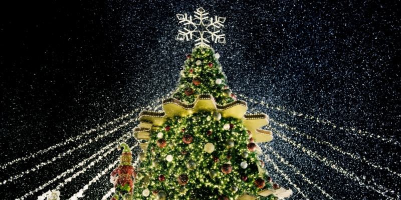 A Christmas tree adorned with snow and colorful lights, set against the backdrop of the Christmas Jersey Shore in Long Branch.