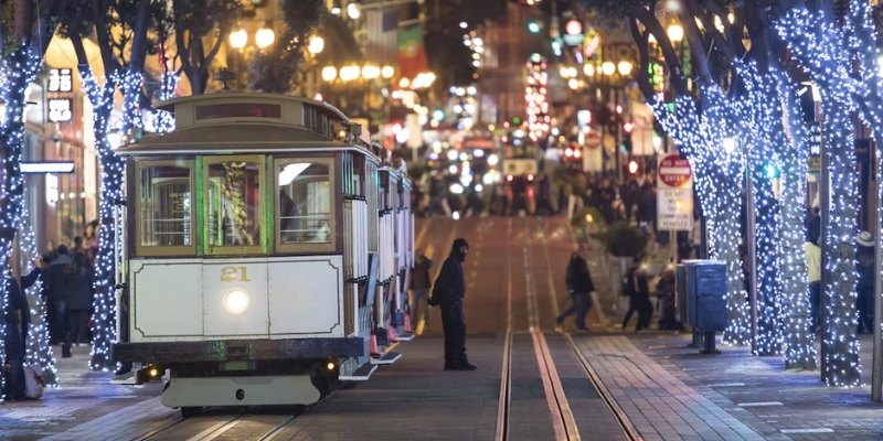 A trolley moves through a street illuminated with Christmas lights, capturing the holiday spirit at the Jersey Shore.