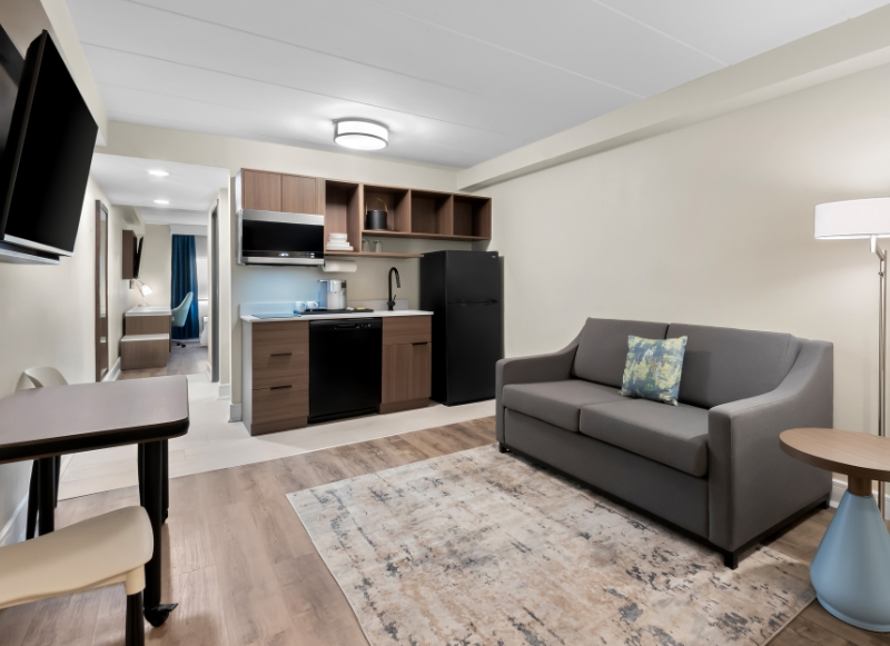 A cozy hotel living room featuring a couch, television, and refrigerator, located near Monmouth Battlefield State Park.