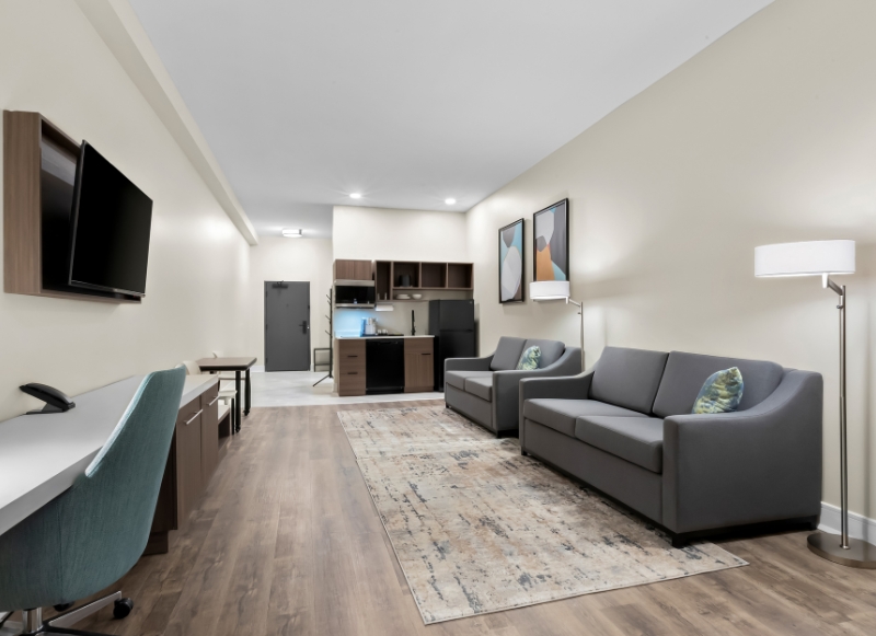 Hotel near Monmouth Mall - 1 Modern hotel room featuring a couch, desk, and television, located near Monmouth Mall.