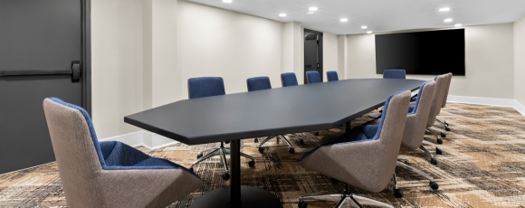 Hotel near Monmouth Mall - Meetings & Events Conference room featuring chairs and a large screen, located in a hotel near Monmouth Mall for meetings and events.