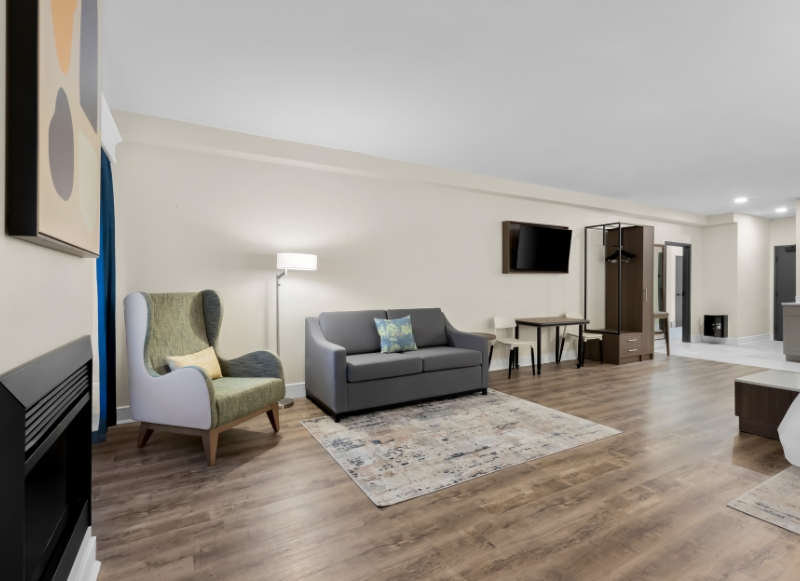 Modern hotel room featuring a couch, television, and fireplace, located near Monmouth Museum.