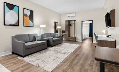 Cozy hotel room with a couch, chair, and TV, situated near Monmouth Museum, designed with all-suite layouts.