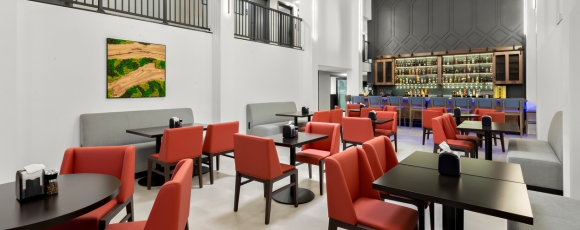 Modern restaurant featuring red chairs and tables, located at a hotel near Trump National Golf Club with onsite dining.