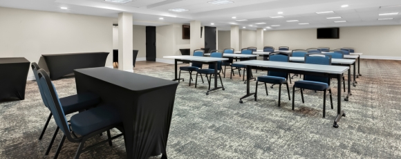 Conference room with tables and chairs, set for meetings at a hotel near Trump National Golf Club.
