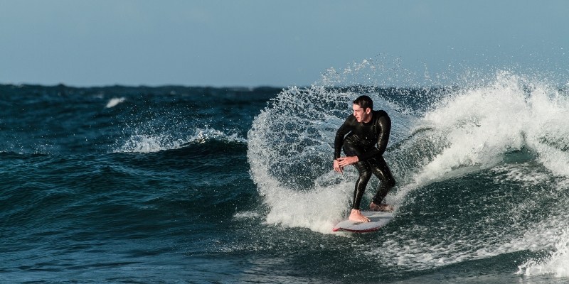 A surfer in a wetsuit rides a wave at Jersey Shore in autumn, capturing the essence of seasonal surfing.