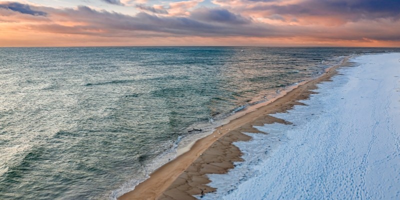A snowy beach at sunset, showcasing the serene beauty of the Jersey Shore in winter.
