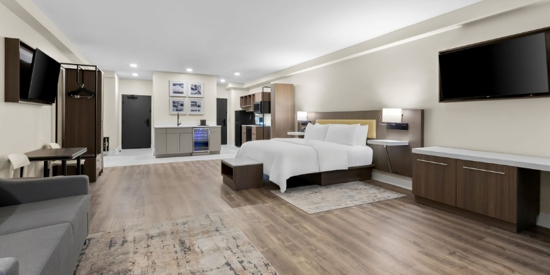 A modern hotel room featuring a bed, desk, and television located at Latitude Suites, ideal for winter stays at the Jersey Shore.