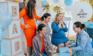 A joyful gathering of women at a baby shower, enjoying refreshments and decorations in a designated meeting area.
