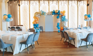 A vibrant event space filled with blue and orange balloons and tables, designed for birthday celebrations.