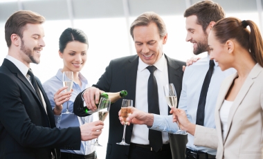 Business professionals toasting with champagne in an office setting, celebrating a corporate holiday party.