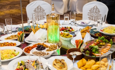 A table set for an Indian wedding breakfast, featuring an array of plates filled with food and various drinks.
