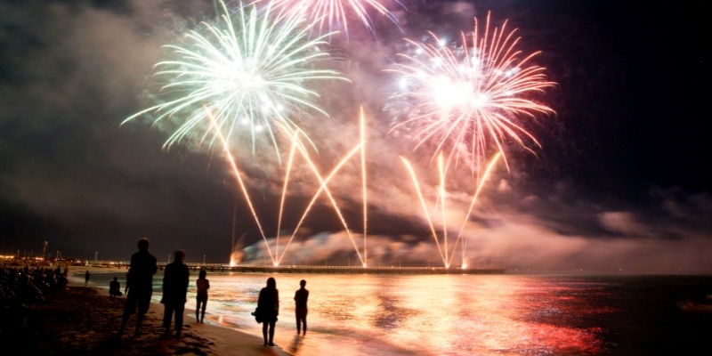 Vibrant fireworks burst above the beach at night, marking New Year’s Eve festivities at the Jersey Shore.