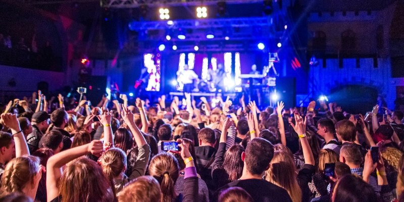 A lively crowd at Asbury Lanes concert on New Year’s Eve, with attendees joyfully raising their hands in celebration.