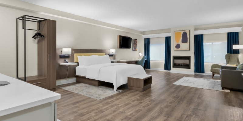 A hotel room featuring a bed, desk, and television, showcasing the comfort of Latitude Suites at the Jersey Shore.