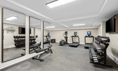 A fitness center featuring mirrors and various gym equipment, located in a hotel near Twin Lights Historic Site.