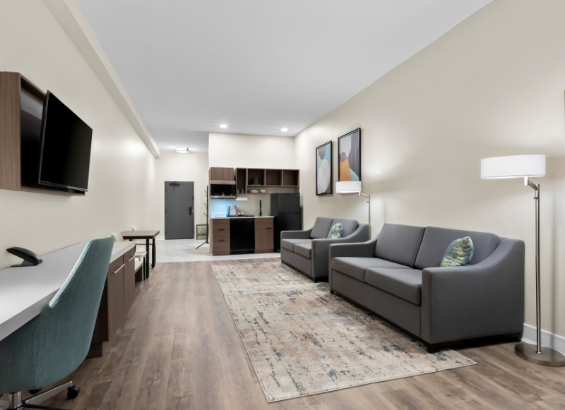 Modern hotel room featuring a couch, desk, and television, ideal for guests staying near Victory Stables.