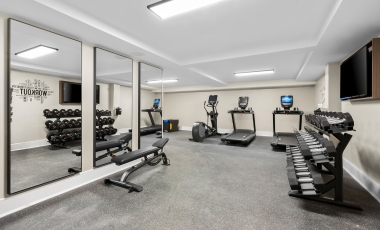 A well-equipped gym with mirrors, showcasing fitness equipment in a 600 sq ft space at a hotel near Shark River Golf Course.