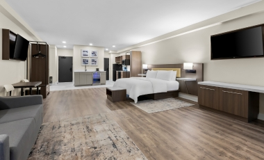 Stylish hotel room showcasing a bed, desk, and television, conveniently located near Shark River Golf Course with spacious suites.