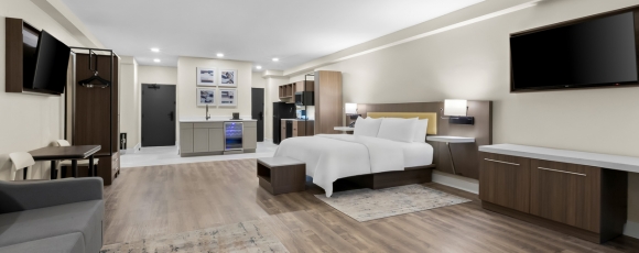 Comfortable hotel room with a bed, desk, and television, ideal for extended stays near Shark River Park.