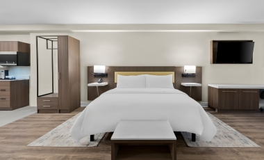 Spacious hotel suite with a bed, desk, and kitchen, located near Shark River Park.