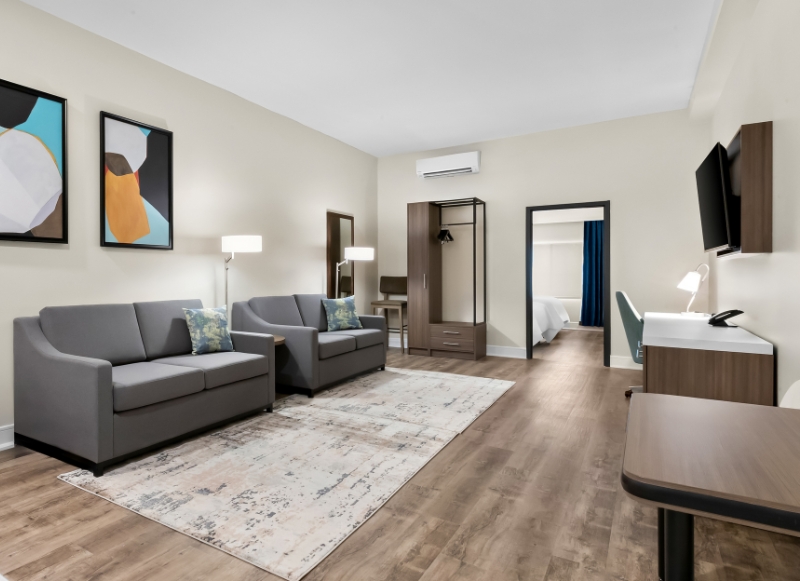 Hotel room showcasing a couch, chair, and television, conveniently located near Twin Lights State Historic Site.