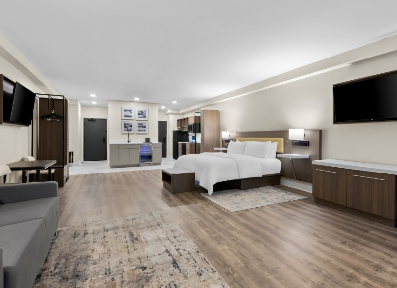 An expansive studio-style hotel suite with a kitchenette, workspace, and modern amenities, ideal for extended business stays near Commvault at Latitude Suites.