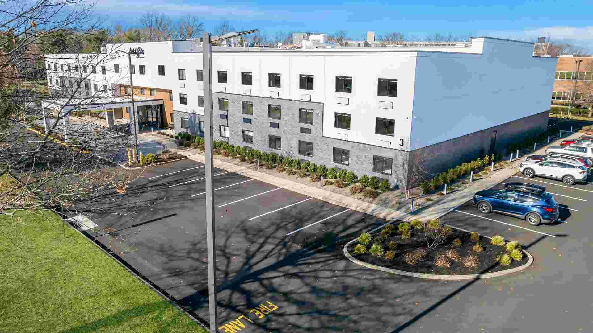An aerial exterior view of Latitude Suites showcasing the modern building design and convenient guest parking near PNC Bank Arts Center.