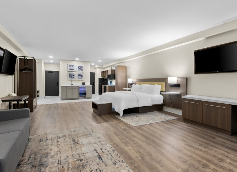 Modern hotel room featuring a bed, desk, and television, located near Eatontown, NJ.