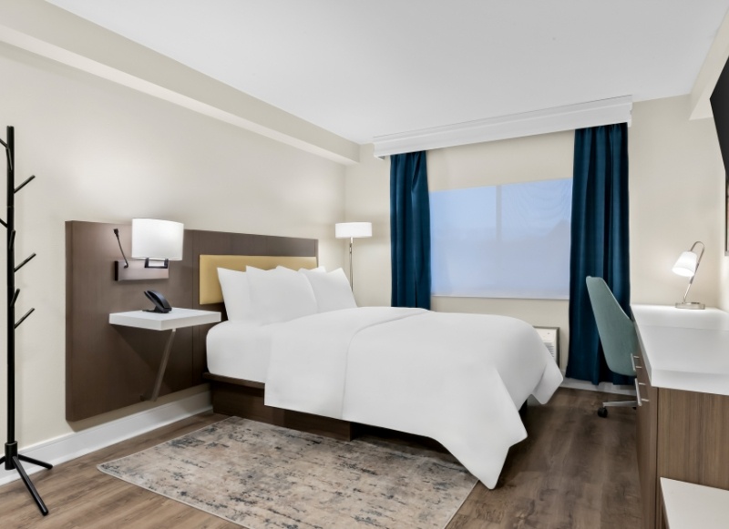 A hotel room featuring a bed, desk, and television, located at Latitude Suites hotel near Jersey Shore Premium Outlets.