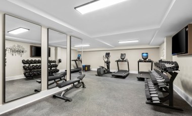 A well-equipped fitness room with mirrors, situated in a hotel close to Keansburg Amusement Park.