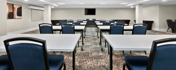 A well-equipped conference room with tables and chairs, ideal for events at a hotel located near MetLife Stadium.