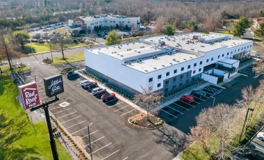 Exterior view of a hotel in a parking lot, featuring signage for free self-parking near Paramount Theatre, Asbury Park.