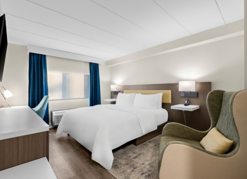 A cozy hotel room with a bed, chair, and television, conveniently near Sea Girt Lighthouse.