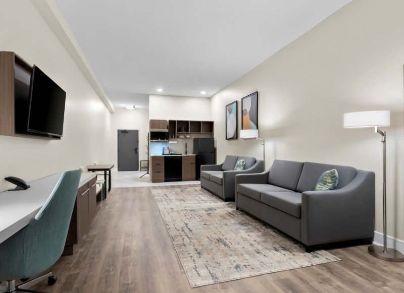 Modern hotel room featuring a couch, desk, and television, located near Shark River Park.